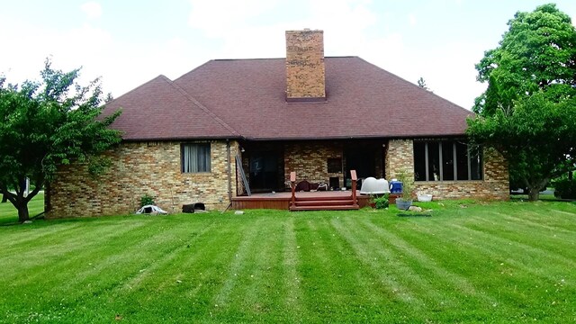 7407 Beecher Rd, Flint, MI 48532 - back of house featuring a wooden deck, a chimney, and a lawn