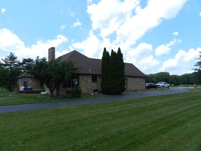 7407 Beecher Rd, Flint, MI 48532 - view of home's exterior featuring a yard, a chimney, and stone siding