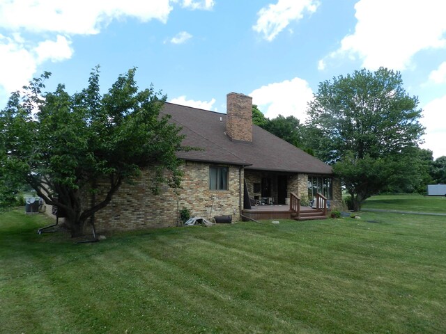 7407 Beecher Rd, Flint, MI 48532 - rear view of property featuring a yard, a chimney, a wooden deck, and brick siding