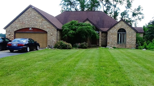 7407 Beecher Rd, Flint, MI 48532 - french country home with brick siding, a garage, a front lawn, and asphalt driveway