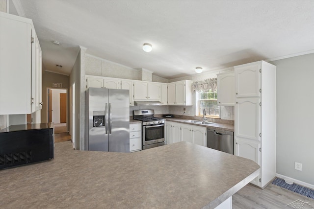 kitchen with crown molding, a sink, a peninsula, stainless steel appliances, and light wood-style flooring