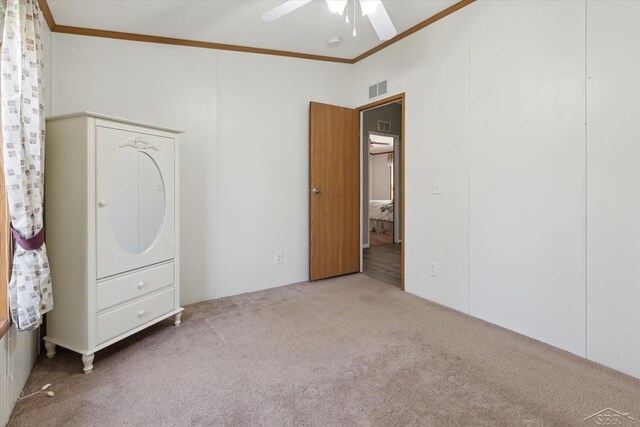 unfurnished bedroom featuring crown molding, a ceiling fan, carpet flooring, and visible vents