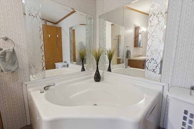 bathroom featuring vanity, toilet, and wallpapered walls