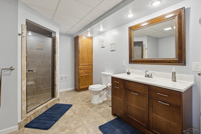 bathroom featuring a shower stall, vanity, baseboards, toilet, and a drop ceiling