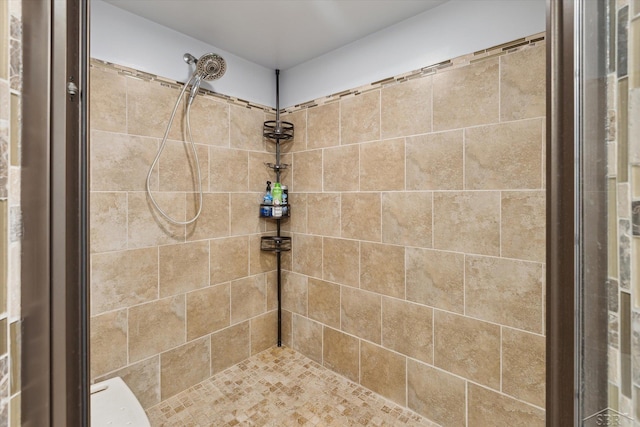 full bath with toilet and a tile shower