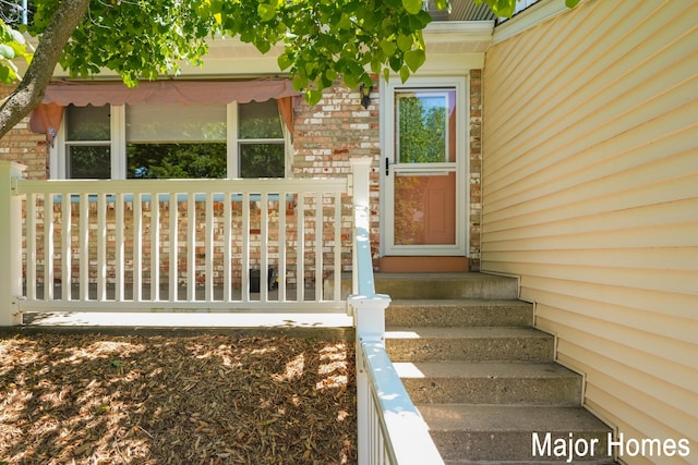 property entrance with brick siding and covered porch