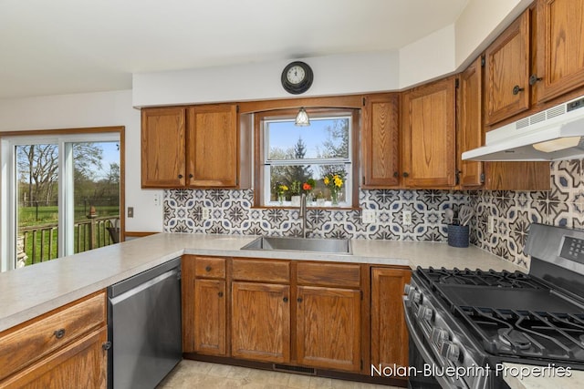 kitchen with a sink, appliances with stainless steel finishes, under cabinet range hood, and light countertops