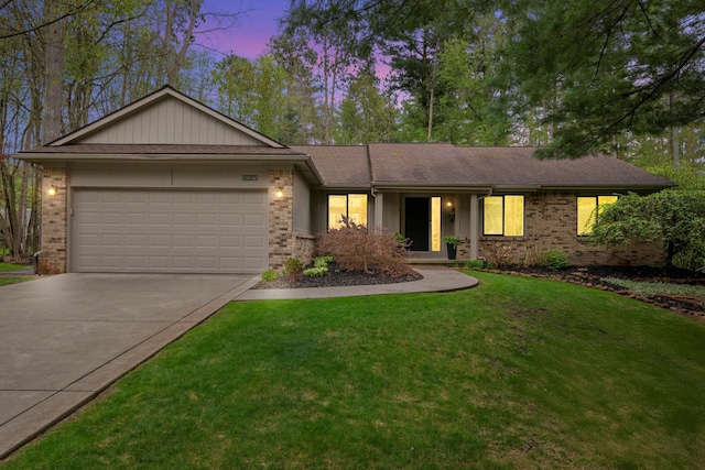 ranch-style home featuring concrete driveway, brick siding, an attached garage, and a yard