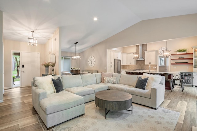 living room featuring light wood-style floors, a chandelier, and vaulted ceiling