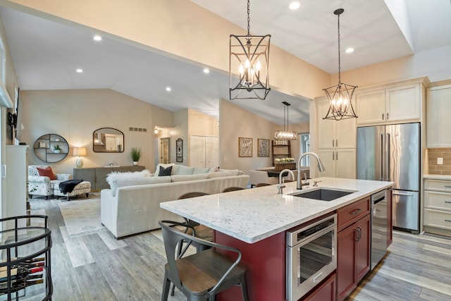kitchen featuring a chandelier, appliances with stainless steel finishes, vaulted ceiling, a sink, and open floor plan