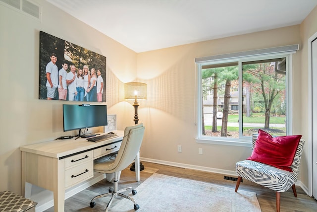 office with baseboards, visible vents, a healthy amount of sunlight, and light wood-style flooring