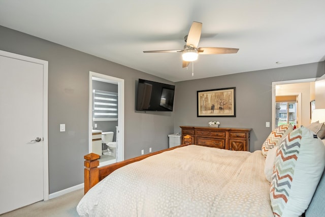 bedroom with light colored carpet, a ceiling fan, baseboards, and ensuite bath