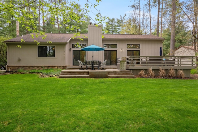 back of property featuring a lawn, a shingled roof, a chimney, and a deck