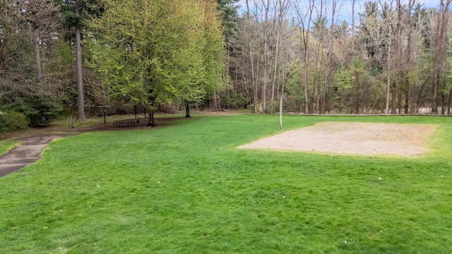 surrounding community with a lawn and a view of trees