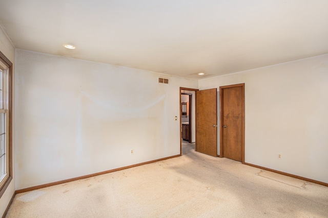 empty room featuring light colored carpet, recessed lighting, baseboards, and visible vents