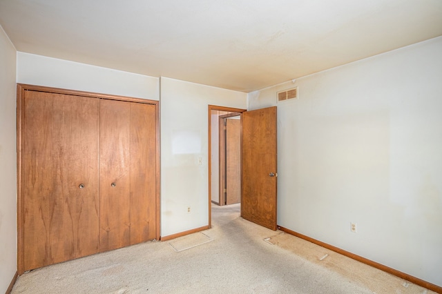 unfurnished bedroom featuring baseboards, light carpet, a closet, and visible vents