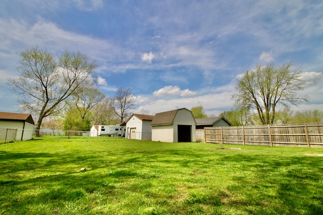 view of yard with an outdoor structure, a fenced backyard, and a shed