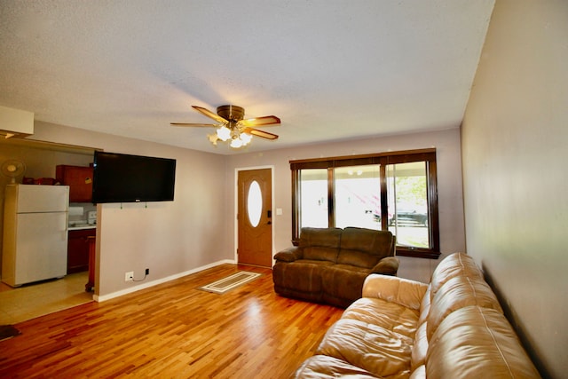 living area with a ceiling fan, baseboards, visible vents, and light wood-style floors
