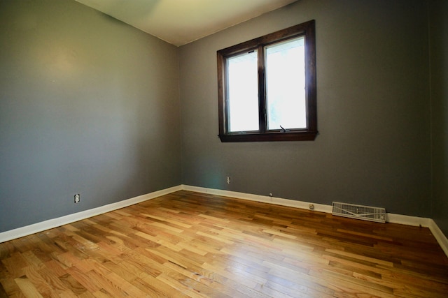 spare room featuring baseboards, visible vents, wood finished floors, and vaulted ceiling