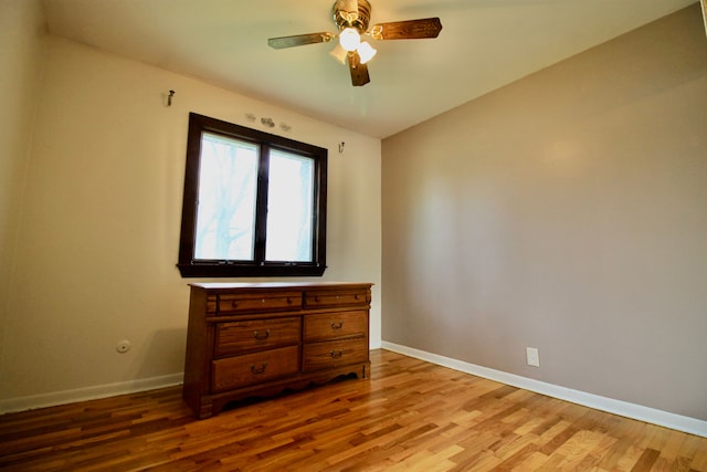 spare room with baseboards, ceiling fan, and light wood-style floors