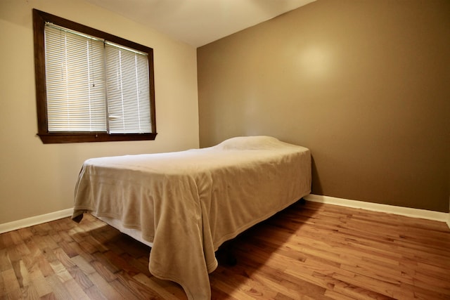 bedroom featuring baseboards, wood finished floors, and lofted ceiling