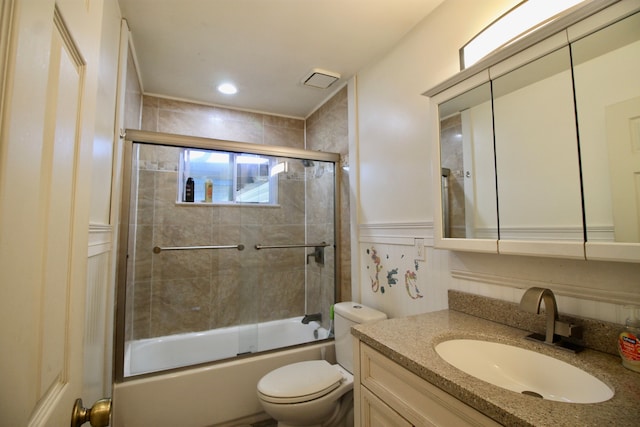 bathroom with toilet, a wainscoted wall, bath / shower combo with glass door, and vanity