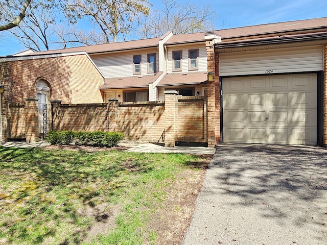 view of front of house featuring a garage, fence private yard, driveway, and brick siding