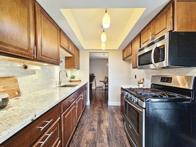 kitchen with light stone countertops, a sink, dark wood finished floors, stainless steel appliances, and baseboards
