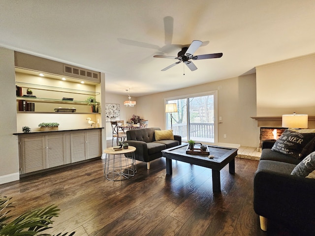 living room with a lit fireplace, a ceiling fan, dark wood-style floors, and visible vents