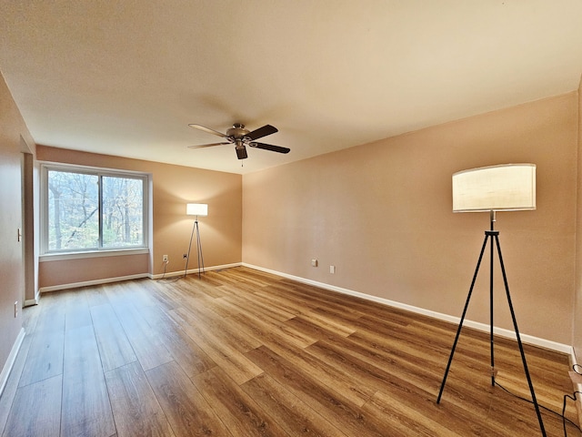 empty room featuring baseboards, ceiling fan, and wood finished floors