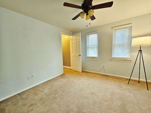 carpeted spare room featuring baseboards, a ceiling fan, and visible vents