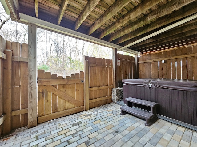 view of patio / terrace with a hot tub, fence, and a gate