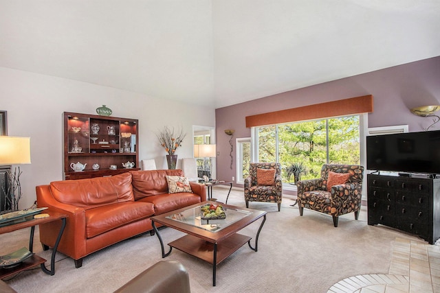 living area with high vaulted ceiling and light carpet