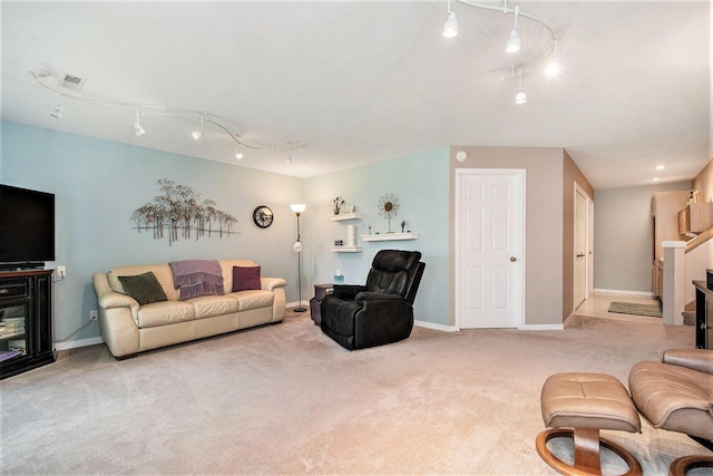 carpeted living area featuring track lighting, baseboards, a fireplace, and visible vents