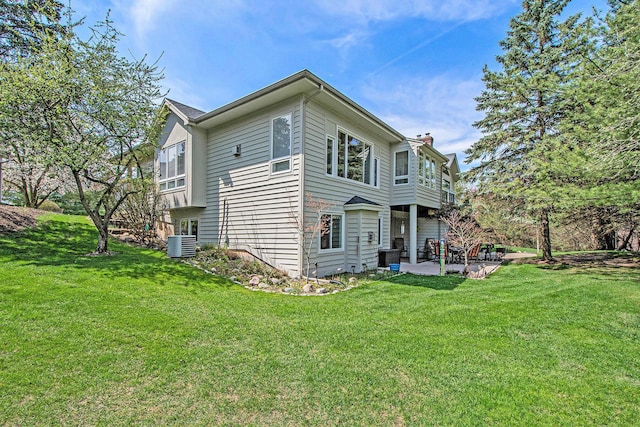 exterior space featuring a patio, central AC unit, a lawn, and a chimney