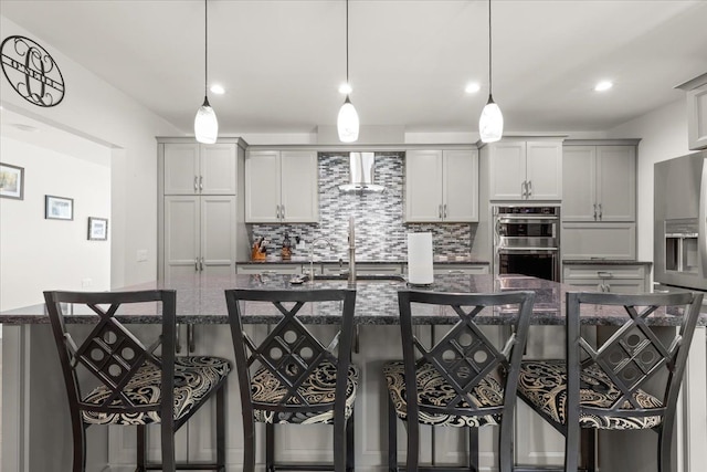 114 Bernstadt St, Novi, MI 48377 - kitchen with backsplash, a kitchen bar, a large island, stainless steel appliances, and wall chimney exhaust hood