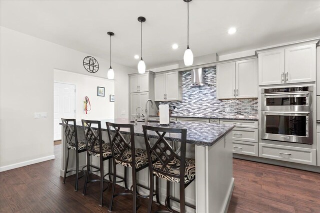 114 Bernstadt St, Novi, MI 48377 - kitchen featuring double oven, a kitchen breakfast bar, dark wood-type flooring, wall chimney exhaust hood, and backsplash