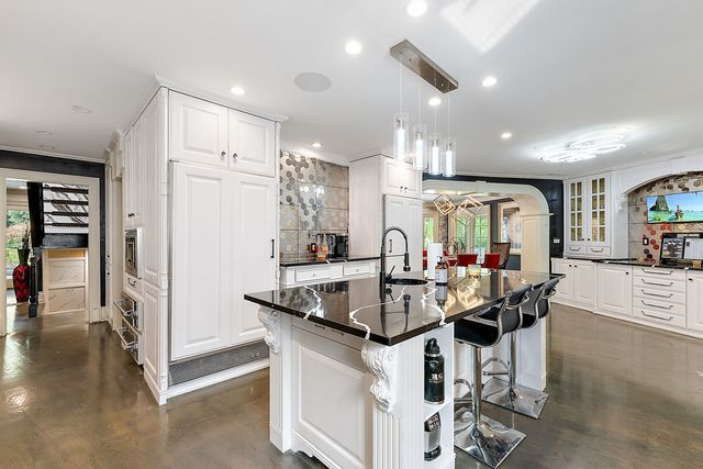 362 Keswick Rd, Bloomfield Hills, MI 48304 - kitchen with decorative backsplash, a healthy amount of sunlight, a breakfast bar area, white cabinetry, and a sink
