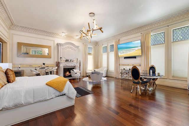 362 Keswick Rd, Bloomfield Hills, MI 48304 - bedroom with an inviting chandelier, crown molding, wood finished floors, and a warm lit fireplace