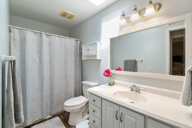 bathroom with toilet, visible vents, wood finished floors, and vanity