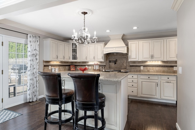 kitchen featuring a notable chandelier, custom range hood, dark wood-type flooring, a kitchen island, and glass insert cabinets