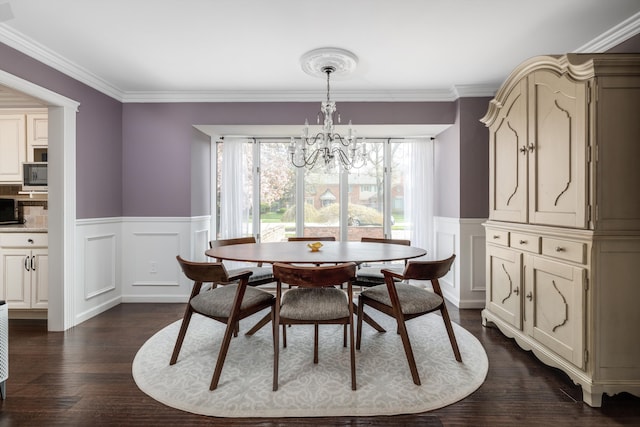 dining area featuring a wainscoted wall, dark wood-style floors, a notable chandelier, ornamental molding, and a decorative wall