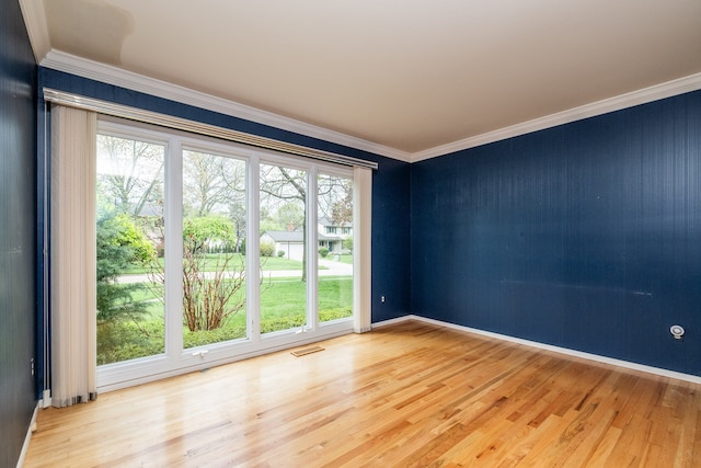 unfurnished room with wood finished floors, ornamental molding, and baseboards