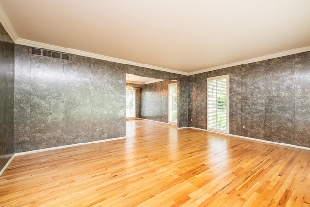 empty room featuring wood finished floors, crown molding, and baseboards