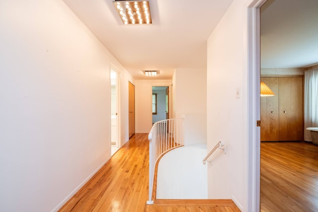 hallway featuring an upstairs landing, light wood-style flooring, and baseboards