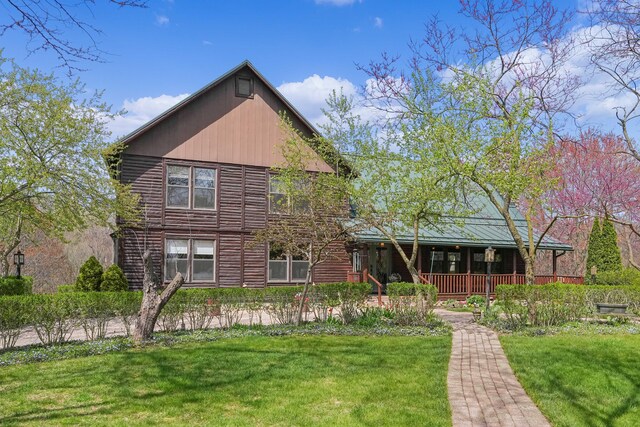 view of front of house with log exterior, covered porch, and a front yard