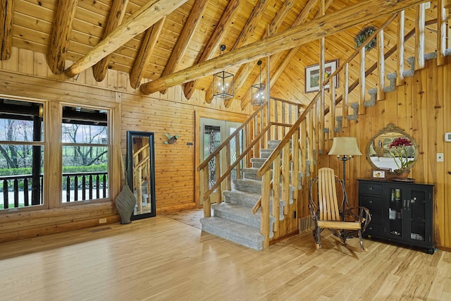 interior space featuring wood walls, stairs, wood finished floors, beam ceiling, and wooden ceiling