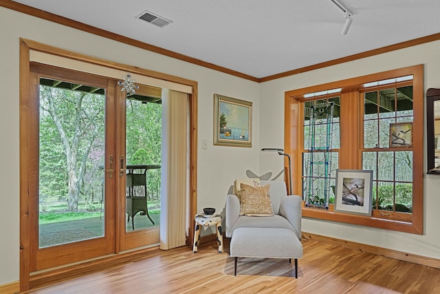 sitting room featuring visible vents, ornamental molding, track lighting, light wood-style floors, and baseboards