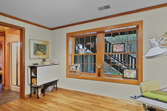 interior space with visible vents, ornamental molding, and wood finished floors