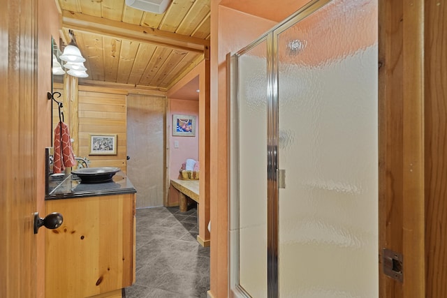 bathroom featuring vanity, tile patterned floors, wood walls, wooden ceiling, and a stall shower